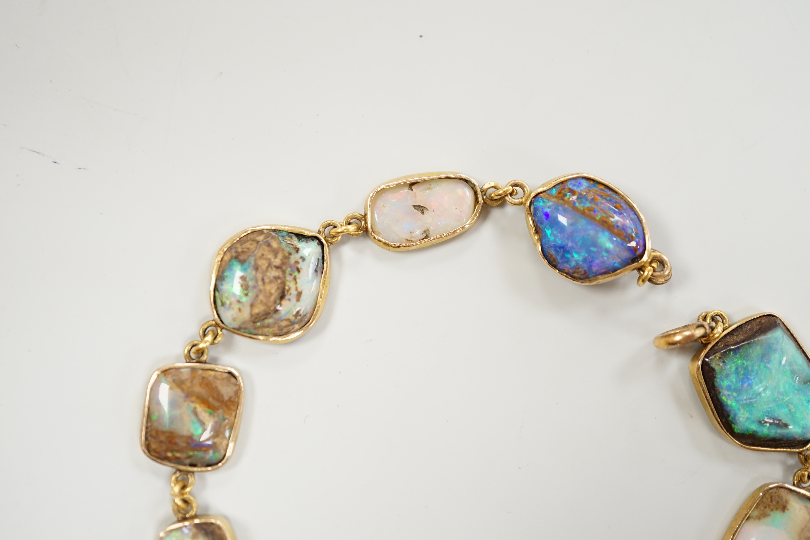 An early 20th century yellow metal and opal set bracelet, of various shapes and hung with central 15ct and diamond chip set charm, 21cm, gross weight 15 grams.